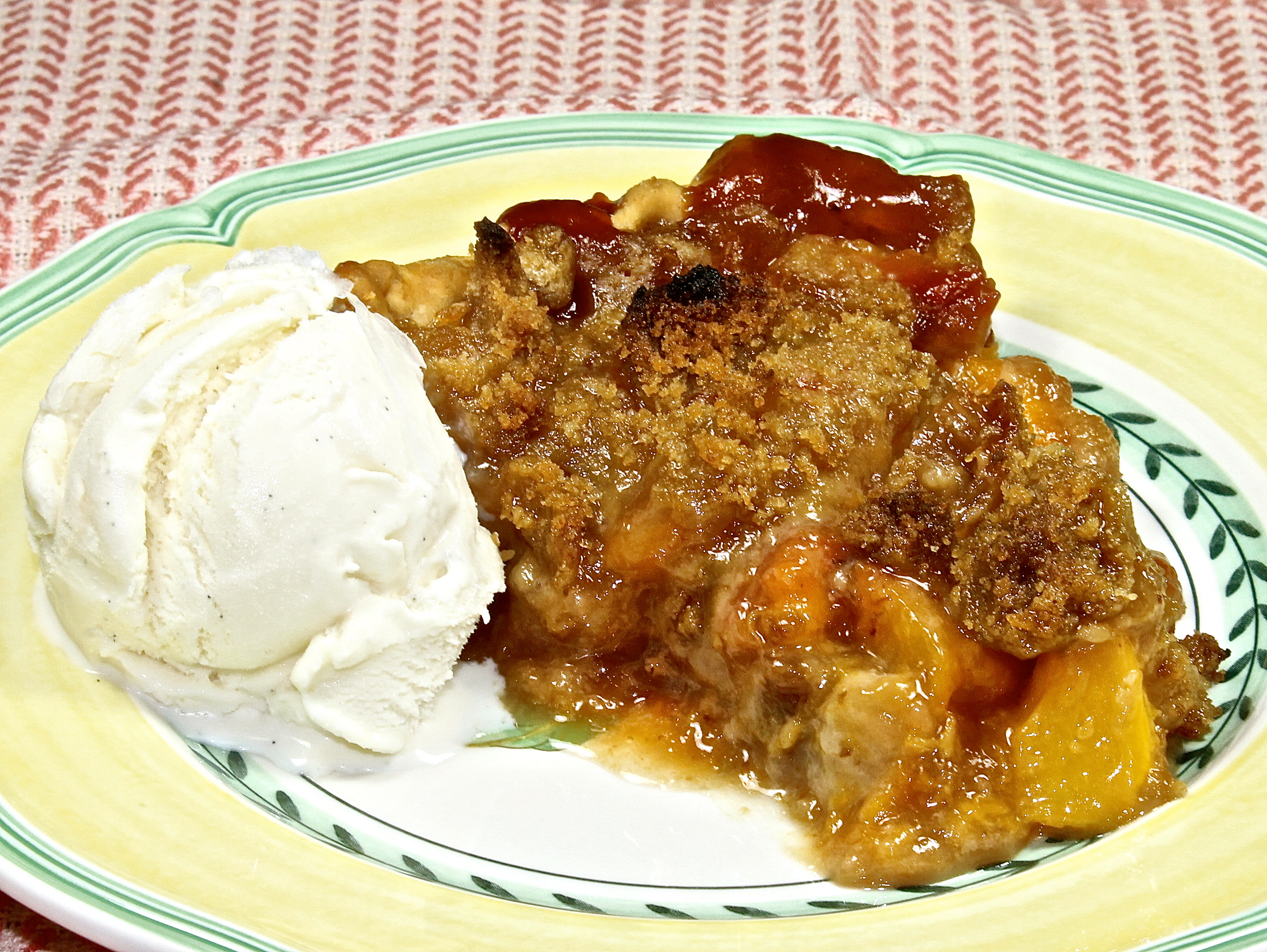 a slice of ginger peach pie with streusel topping and a scoop of vanilla bean ice cream