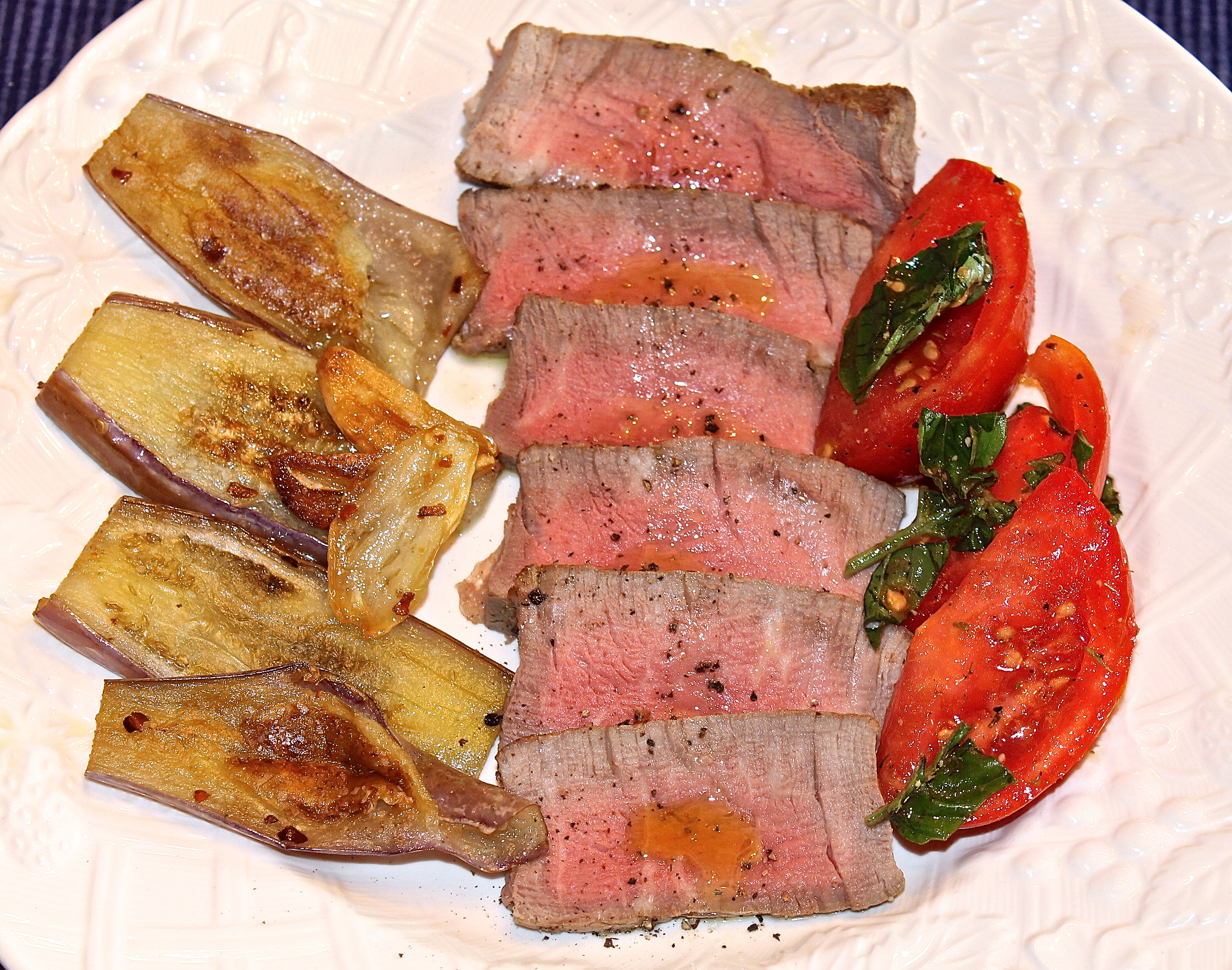 Sliced Filet Mignon Drizzled With Extra Virgin Olive Oil Served Room Temperature With Sautéed Baby Eggplant And A Basil And Tomato Salad