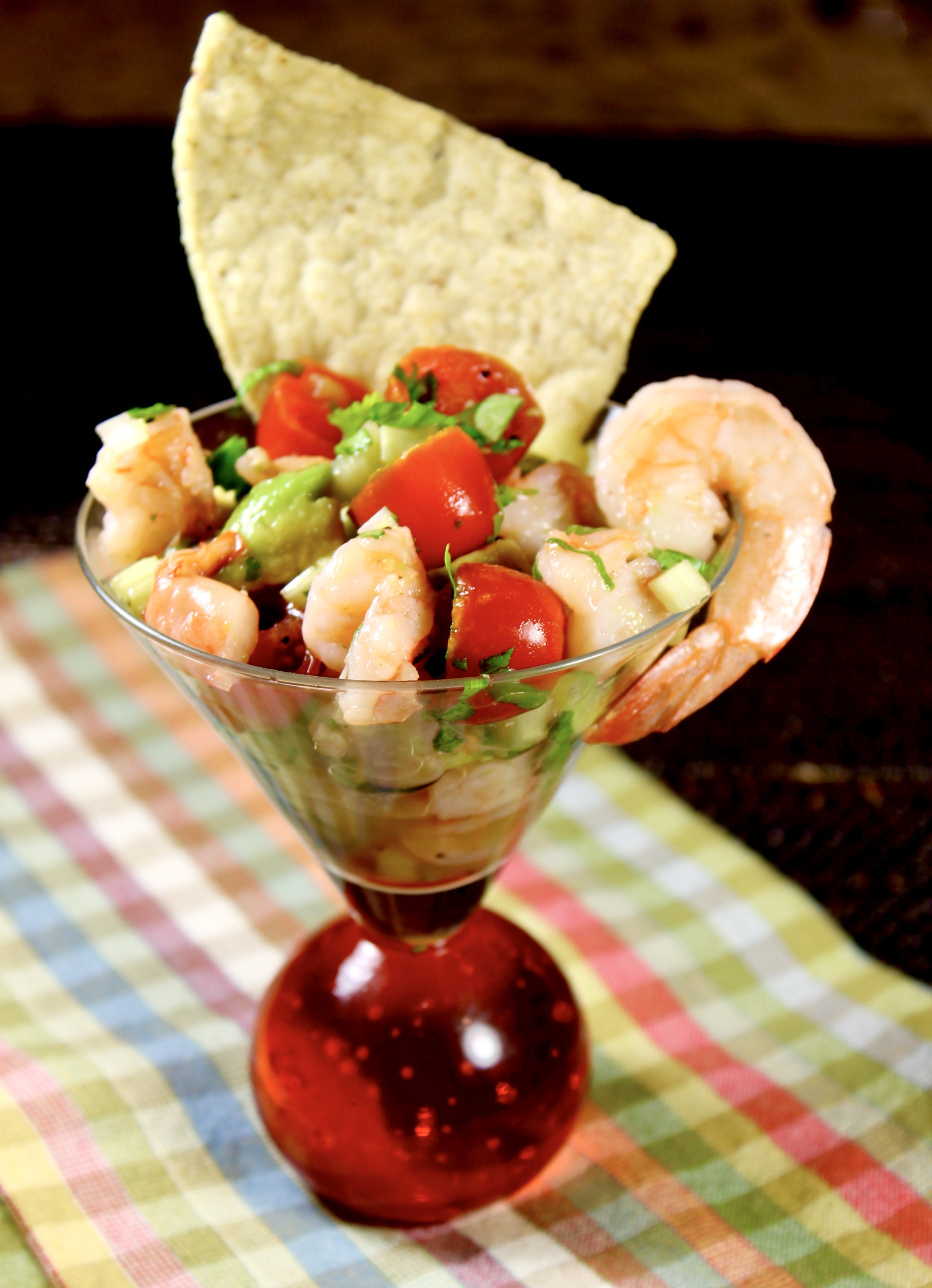 A refreshing Mexican shrimp cocktail served in a martini  glass, garnished with whole shrimp and crisp tortilla chip