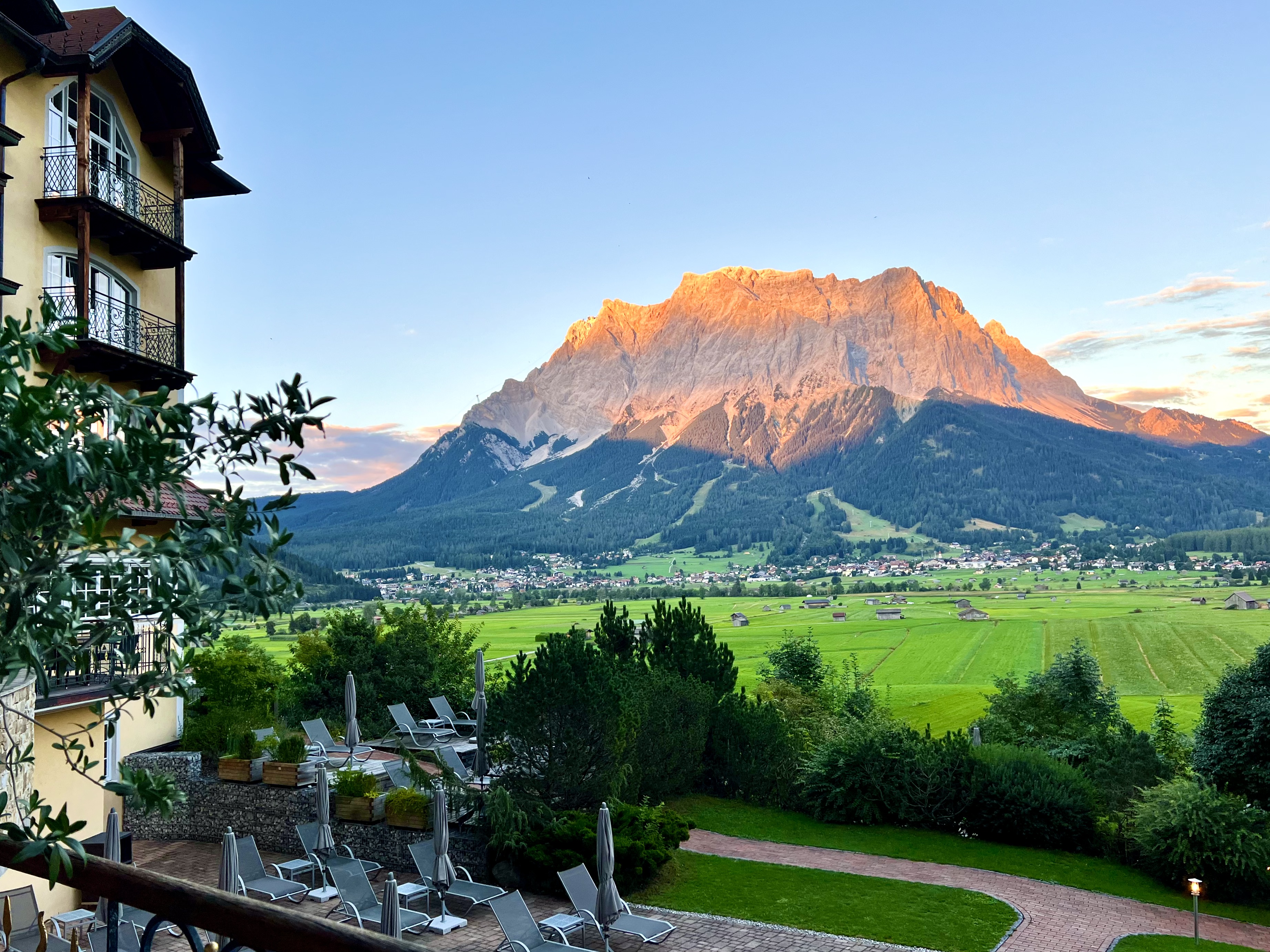 Luxury outdoor heated pool at Hotel Post Lermoos facing the massive snow covered Zugspitze mountain peak in Austria